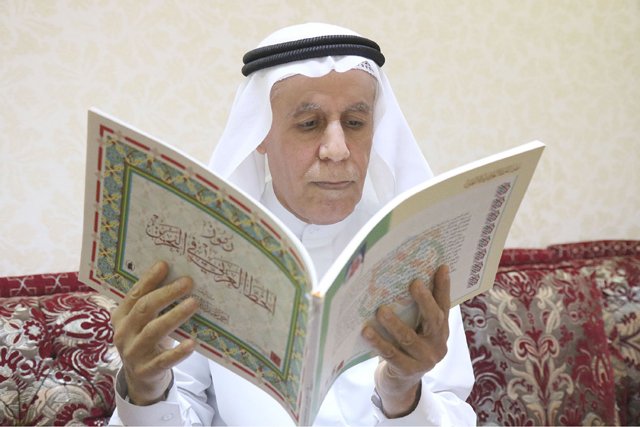 المؤلف ممسكاً بكتاب «رموز الخط العربي في البحرين» 